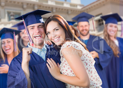 Proud Male Graduate In Cap and Gown with Girl Among Other Graduates