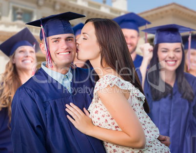 Proud Male Graduate In Cap and Gown with Girl Among Other Graduates