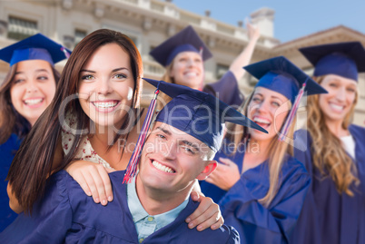 Proud Male Graduate In Cap and Gown with Girl Among Other Graduates