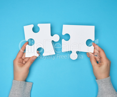 two female hands holding big paper white blank puzzles