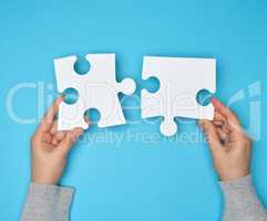 two female hands holding big paper white blank puzzles