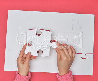 female hand puts white big puzzles on a pink background