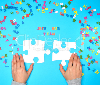 women's hands hold two large white puzzles and the inscription j