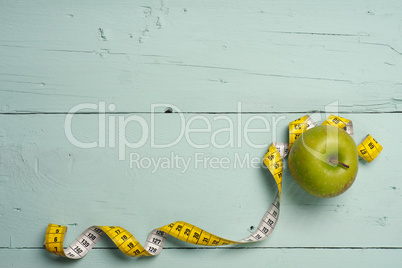 Fresh green apple with measuring tape on wood
