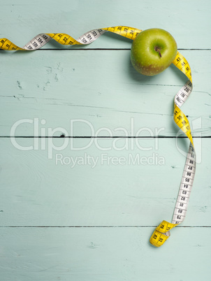 Fresh green apple with measuring tape on wood