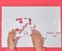 female hand holding white puzzle with the word solution