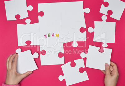 female hand puts white big puzzles on a red background