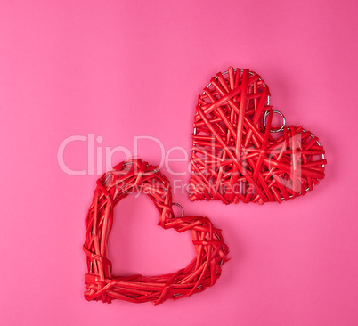 two wicker red hearts on a pink background