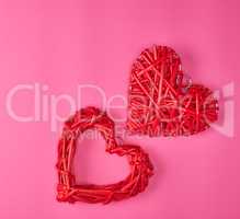 two wicker red hearts on a pink background