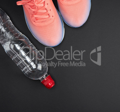 pink sports sneakers and a water bottle on a black background