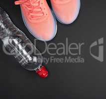 pink sports sneakers and a water bottle on a black background