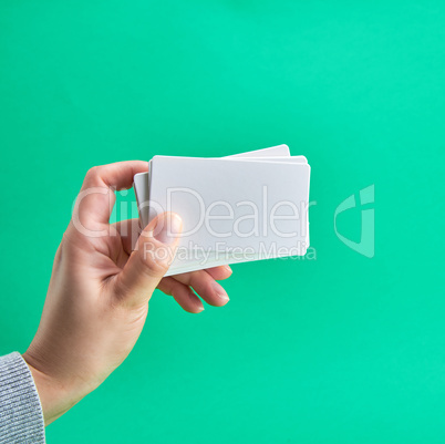 white paper business card in a female hand on a green background