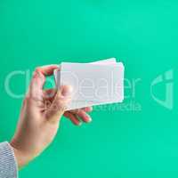 white paper business card in a female hand on a green background