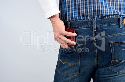 man in a blue plaid shirt and jeans puts a leather wallet in his