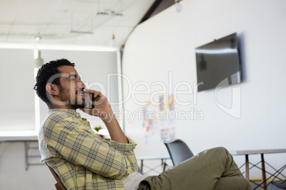 Relaxed man talking on phone in office