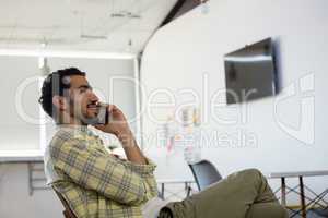 Relaxed man talking on phone in office