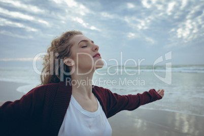 Beautiful woman standing arm stretched at beach