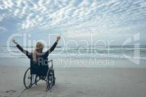 Woman disable sitting with open arm on wheelchair at beach