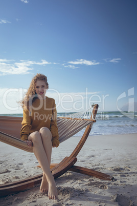 Woman looking at camera sitting on hammock at beach