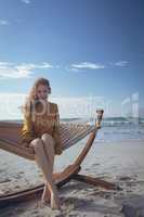 Woman looking at camera sitting on hammock at beach