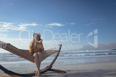 Young woman sitting on hammock at beach