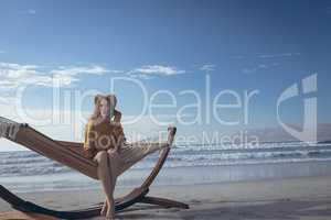 Young woman sitting on hammock at beach