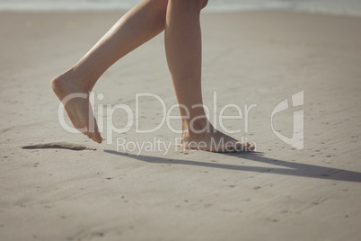 Woman walking on sand with barefoot at beach