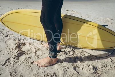 Male surfer standing on sand at beach