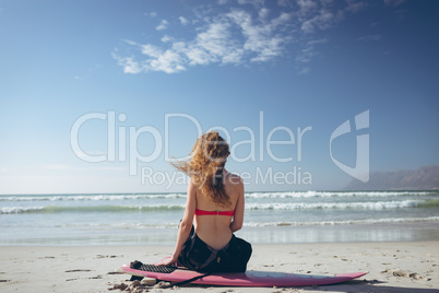 Female surfer sitting on surfboard at beach