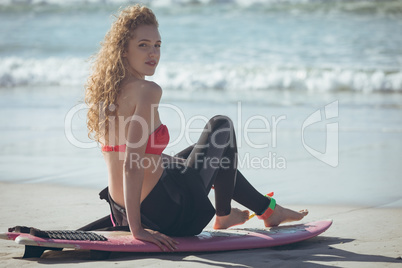Female surfer sitting on surfboard at beach
