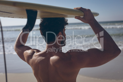 Male surfer carrying his surfboard at beach