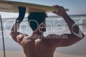 Male surfer carrying his surfboard at beach