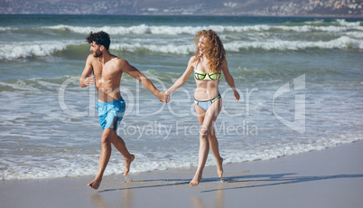 Couple holding hands and running on beach