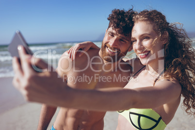 Couple taking selfie standing at beach