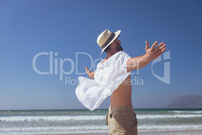 Happy man standing with open arm at beach