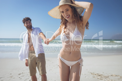 Couple holding hand while standing at beach