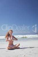 Woman practicing yoga in lotus position at beach