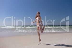 Attractive woman standing on tip toe at beach