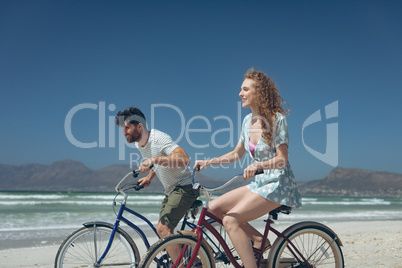 Happy couple riding bicycle at beach on a sunny day