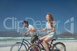 Happy couple riding bicycle at beach on a sunny day