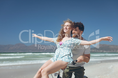 Happy Caucasian couple enjoying on bicycle at beach