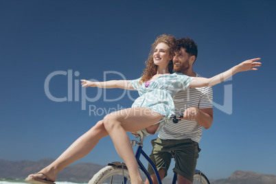 Happy couple enjoying on bicycle at beach on a sunny day