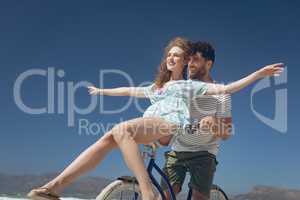 Happy couple enjoying on bicycle at beach on a sunny day
