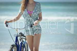 Young woman holding bicycle at beach on a sunny day