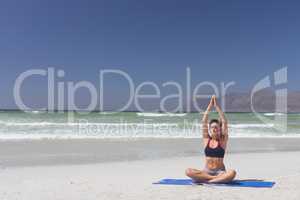 Young woman practicing yoga on the sand at beach