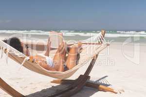 Woman relaxing on hammock at beach on a sunny day