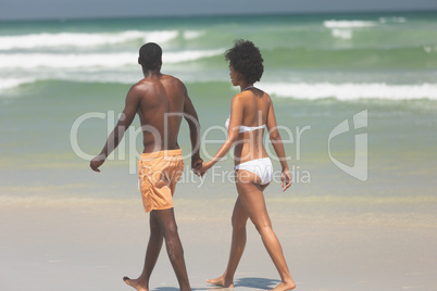 Couple holding hands and walking at beach on a sunny day