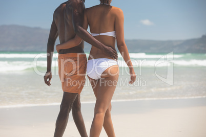 Couple walking with arm around at beach