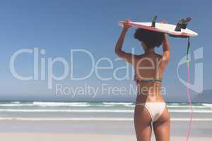 Female surfer carrying surfboard at beach