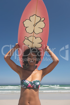 Female surfer carrying surfboard at beach